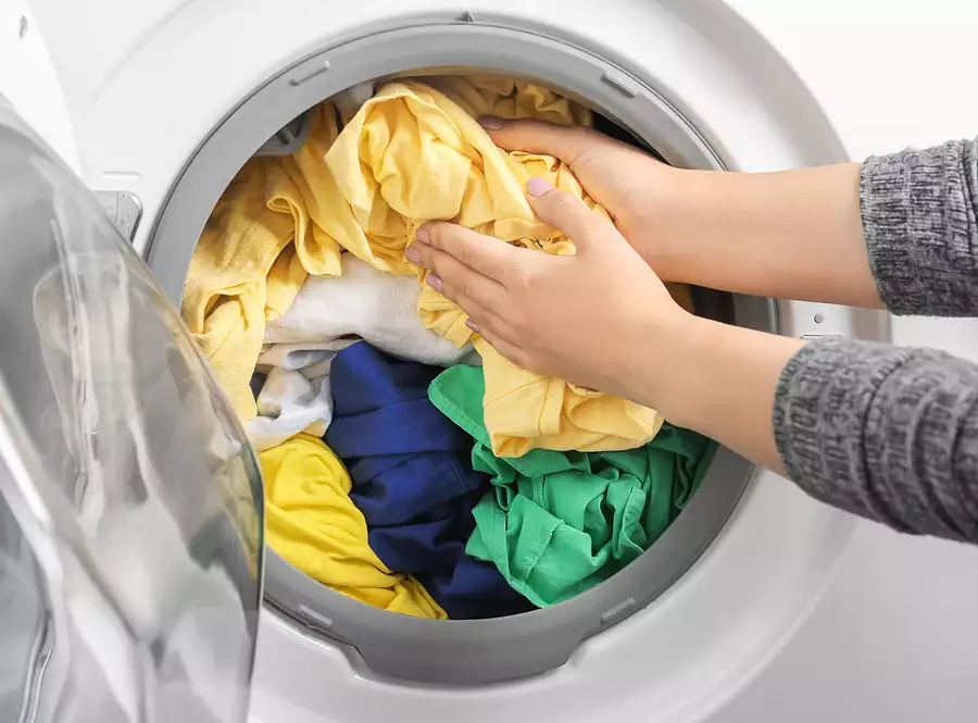 young woman putting clothes overloading the samsung washer